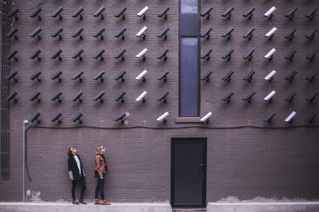 Wall filled with cameras observing folks on street