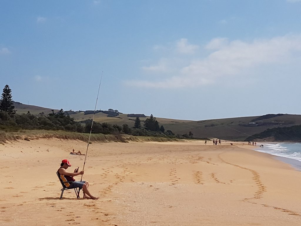 Fisherman on wide sand beach
